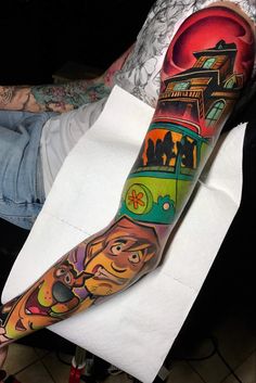 a man's arm with colorful tattoos on it and an image of a bus in the background