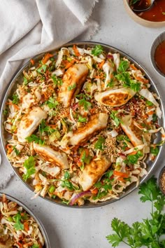 a platter filled with chicken and coleslaw next to two bowls of sauce