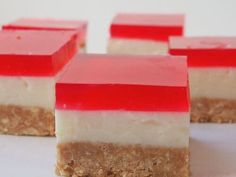 four pieces of cake with red and white frosting on them sitting on a table