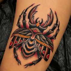 a tattoo on the leg of a woman with an insect design in red and black