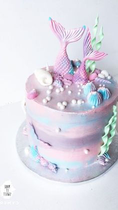 there is a cake decorated with pastel colors and mermaid tail decorations on the top