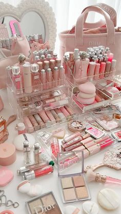 a table topped with lots of pink cosmetics and makeup products on top of each other