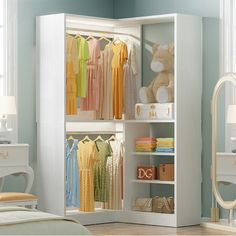 an open closet with clothes and teddy bear on the shelf next to it in a bedroom