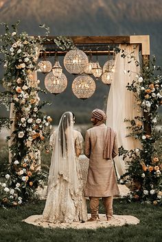 a bride and groom standing in front of an outdoor ceremony arch