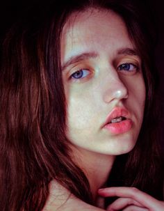 a woman with freckled hair and blue eyes is posing for the camera while holding her hand on her shoulder