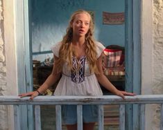 a woman standing on a balcony with her hands on the railing and looking at the camera