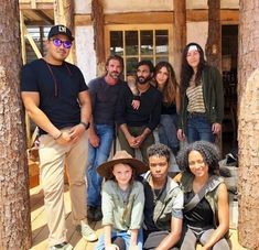 a group of people posing for a photo in front of a building with wooden pillars