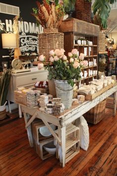 a flower shop with flowers and candles on the table in front of it's counter