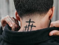 the back of a man's head with a cross tattoo on his upper neck