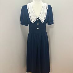 Such A Beautiful Peter Pan Collared Dress. Brand New Never Worn With Tags Attached. It Is A Navy Blue Dress With A White Collar And Pearl Buttons Going Down The Chest. It Is Midi Style Dress With Short Puff Sleeves. Dress Is Size 6 And Is 100 % Polyester And Also Has Pockets. Provided Picture To See How It Looks On, Perfect For Any Occasion! The Dress Retails Way More Then The Price I Have Provided! Navy Retro Dress For Formal Occasions, Retro Navy Dress For Formal Occasions, Navy Retro Formal Dress, Navy Vintage Short Sleeve Dress, Vintage Navy Dress For Formal Occasions, Navy Fitted Dress For Daywear, Fitted Navy Dress For Daywear, Navy Vintage Style Formal Dress, Fitted Navy Midi Dress For Daywear