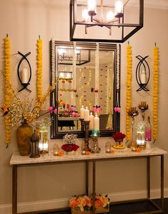 a table with candles and flowers on it in front of a mirror that is hanging from the ceiling