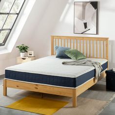 a bed with a wooden frame and mattress in a room next to a yellow rug