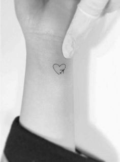 a small heart tattoo on the wrist is shown in this black and white photo,