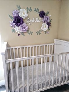 a white crib with purple and white flowers on the wall