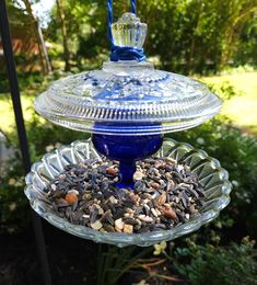 a blue bird feeder with gravel in it