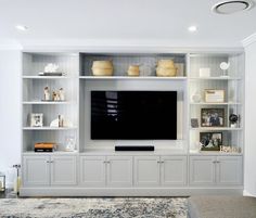 a large entertainment center with built in shelves and a flat screen tv mounted on the wall