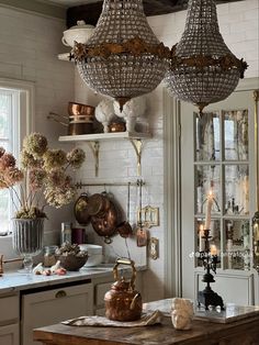 two chandeliers hanging from the ceiling in a kitchen with white walls and cabinets