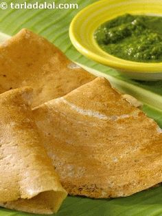 two pita breads on a banana leaf with green dipping sauce in the background