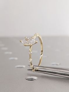 a diamond ring sitting on top of a table next to some scissors and needles in front of it