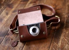 a brown leather camera case sitting on top of a wooden floor