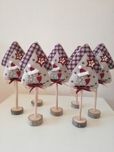 five small christmas trees on wooden bases with red and white plaid fabric hats, bows and stars