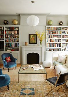 a living room filled with furniture and bookshelves next to a fire place in front of a fireplace