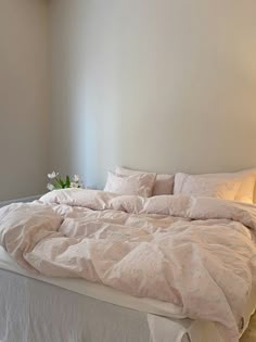 an unmade bed with white sheets and pillows in a bedroom next to a window