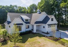 this is an aerial view of the front of a house with white siding and black shingles