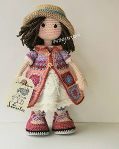 a crocheted doll is wearing a hat and holding a card with the name seletta on it