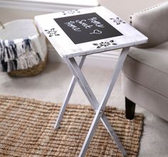 a small table with a chalkboard on it in a living room next to a chair