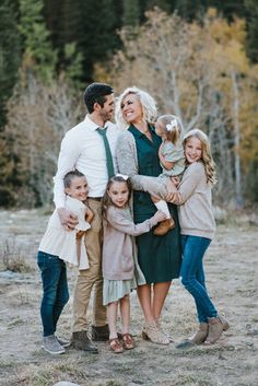 a family posing for a photo in front of some trees with their arms around each other