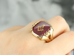 "This large vintage red glass Masonic ring has amazing, yet simply detailed shoulders, rising up from the shank and bending around the corners of the stone. The center is a classic red glass cabochon, inlaid with the gold Masonic symbol, with a nice flat profile. This ring has a substantial feel to it, and makes for a classic Masonic piece! Metal: 14K Yellow Gold Gem: Red Glass Cabochon, Gold Inlaid Masonic Symbol Gem Measures: 16mm x 14mm, Square Cushion Cut Size of Ring: 10 Marks: \"14K\" and Heirloom Red Signet Ring With Polished Finish, Classic Red Signet Ring For Formal Occasions, Classic Red Intaglio Ring, Antique Red Gemstone Signet Ring, Classic Red Gemstone Signet Ring, Classic Red Ruby Signet Ring, Red Signet Ring For Formal Occasions, Vintage Red Signet Ring, Red Formal Signet Ring