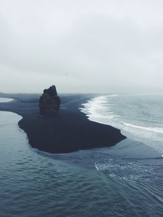 an island in the middle of the ocean with waves crashing on it and rocks sticking out of the water