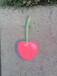 a drawing of a cherry on concrete with grass in the backgroung area