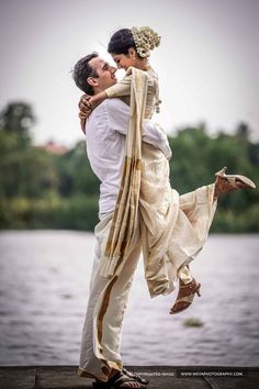 a man and woman are hugging by the water