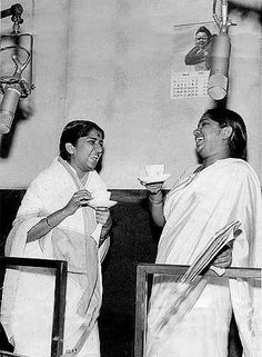 two women in white saris are having tea and smiling at each other while holding cups