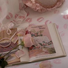 an open book on a bed with pink flowers