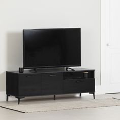 a flat screen tv sitting on top of a black entertainment center next to a white door