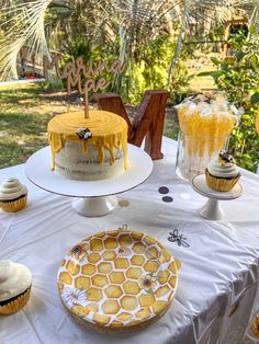 a table topped with cakes and cupcakes on top of a white table cloth