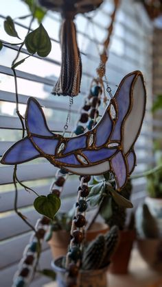 a wind chime hanging from a window next to a potted plant in front of it