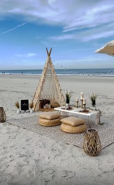 an outdoor seating area on the beach with a teepee tent and wicker chairs