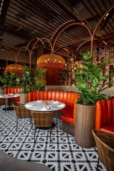 an indoor restaurant with orange leather booths and potted plants