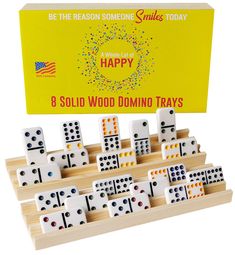 the wooden domino tray is filled with 8 solid wood dominos, and it's in front of a yellow box that says be the reason someone smiles today