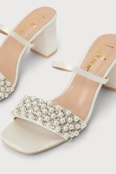 We know that the glamorous allure that the Lulus Karcen Ivory Satin Pearl Rhinestone High Heel Slide Sandals emanate is sure to make them your favorite plus one this wedding season! Sleek woven satin shapes a square toe bed, a slender vamp strap (with a bit of elastic at the side), and a wide toe strap embellished with an array of dreamy faux pearls and shiny clear rhinestones. A low block heel is sure to keep you comfortable so you can keep the party going all night long! 2. 25 wrapped block he Party White Heels With Pearl Embroidery, White Pearl Embellished Bridal Accessories For Party, Elegant Embellished Sandals For Wedding, Pearl White Bridal Accessories For Party, Elegant Embellished Wedding Sandals, Glamorous White Embellished Sandals, White Sparkling Heels For Wedding, Sparkling White Heels For Wedding, Rhinestone Wedding Shoes For Bridal Shower