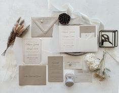 the wedding stationery is laid out on top of each other, including an envelope and ring