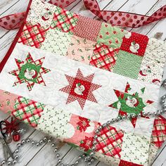 a quilted table runner with red, green and white stars on it next to scissors