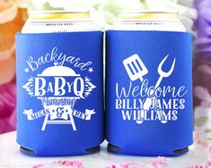 two blue can coolers sitting on top of a table with flowers in the background