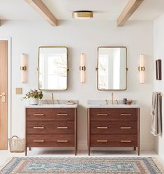 a bathroom with two sinks, mirrors and rug on the floor in front of it