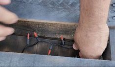 a man is working on some electrical wires in a box with another person's hand