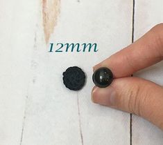 a hand is pointing at two small black rocks on the paper next to each other